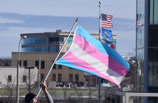 A protester holds a transgender pride flag as part of a 