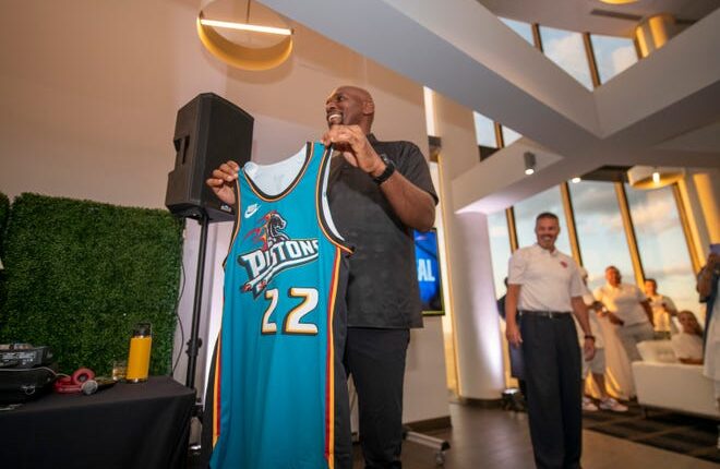 Former Detroit Piston Jerry Stackhouse holds up one of the new jerseys the team will wear this season during a party at the Highlands restaurant in Detroit, July 25, 2022, to officially announce the return of the teal jerseys worn by the players in the '90s .