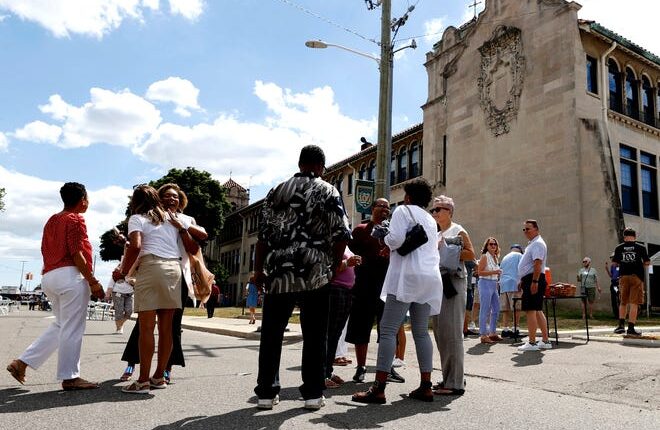 Former students from the Gesu School in Detroit gather and talk outside of their old school during the 100 year celebration at Gesu Catholic Church and School in Detroit on Saturday, July 30, 2022.
