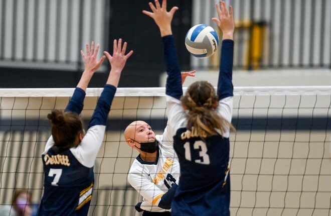 Grand Ledge's Angelia Cutts, center, spikes the ball as DeWitt Gabrielle Stafford, left, and Taya Nordman defend during the fourth set on Thursday, Nov. 4, 2021, at East Lansing High School.