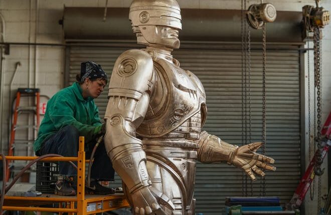 Nadine Chronopoulos works on the grinding and sanding of an 11' RoboCop statue at a warehouse on Detroit's east side on February 24, 2021, while finishing the statue before patina being applied.  The statue will be housed somewhere while waiting for a home to be announced.