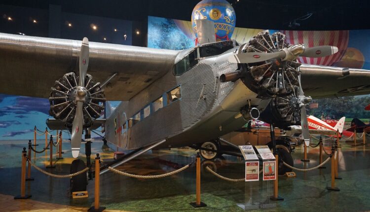 Vintage gray metal aircraft with a nose-mounted engine and beneath each wing sits in a museum