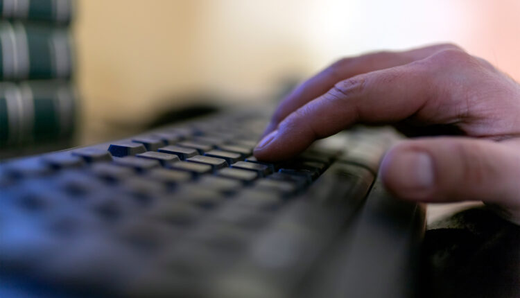 A photo of a hand typing on a computer keyboard.