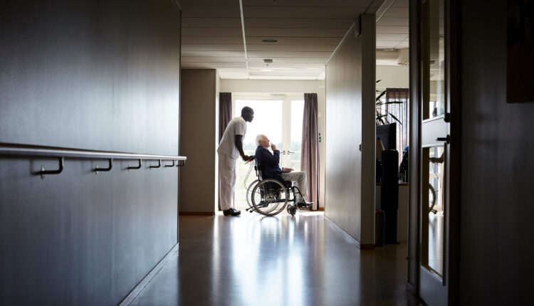 A photo of a nurse pushing an elderly patient in a wheelchair.
